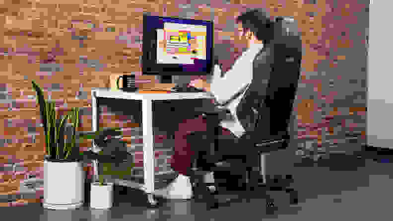 A person sitting on the chair interacting with a desktop.