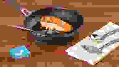 Seared salmon in Circulon ScratchDefense skillet, surrounded by metal utensils and a Reviewed checkmark.