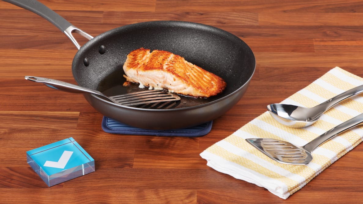 Seared salmon in Circulon ScratchDefense skillet, surrounded by metal utensils and a Reviewed checkmark.