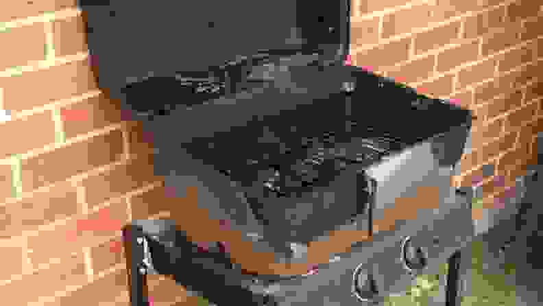 Cheap, rusty grill resting on a brick wall