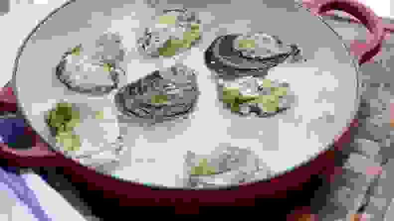 Seven raw oysters are chilling on a bed of crushed ice.