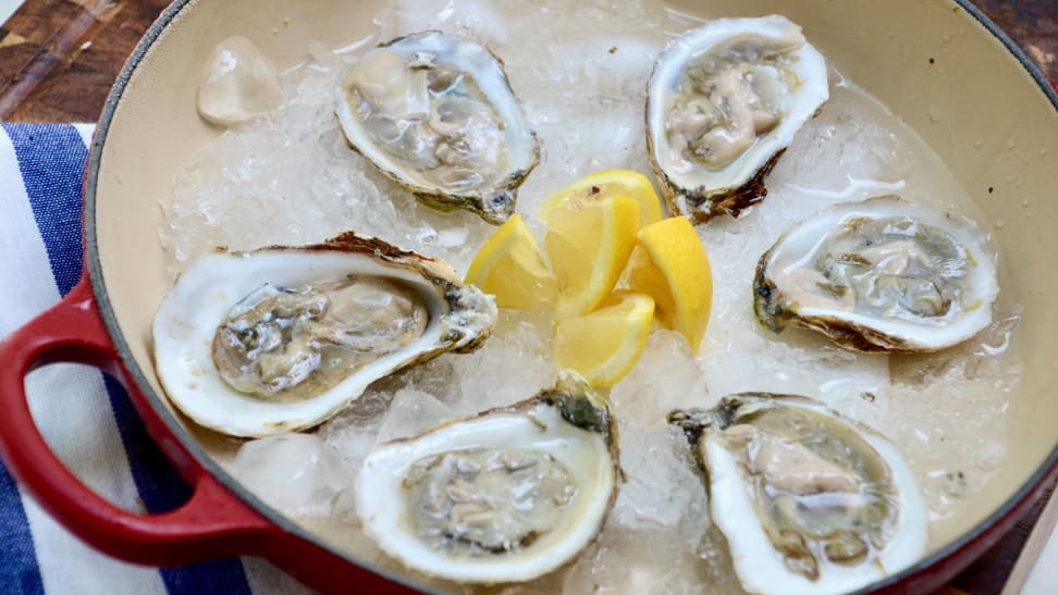 Here's a tray of six oysters on half shells that were shucked moments ago, accompanied by lemon wedges.