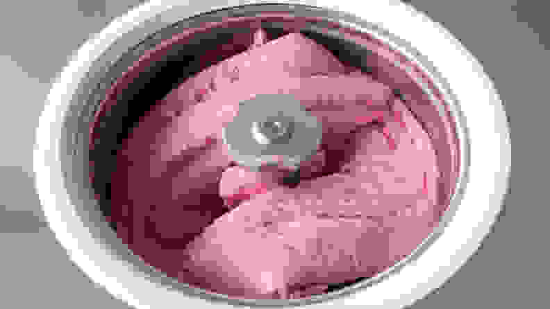 Homemade raspberry ice cream churning in a small professional  ice cream machine.