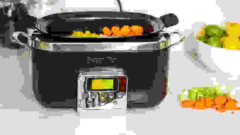 A black GreenPan Slow Cooker is filled with raw vegetables.