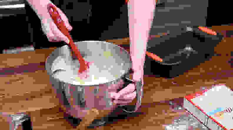 A person mixing batter with a silicone spatula