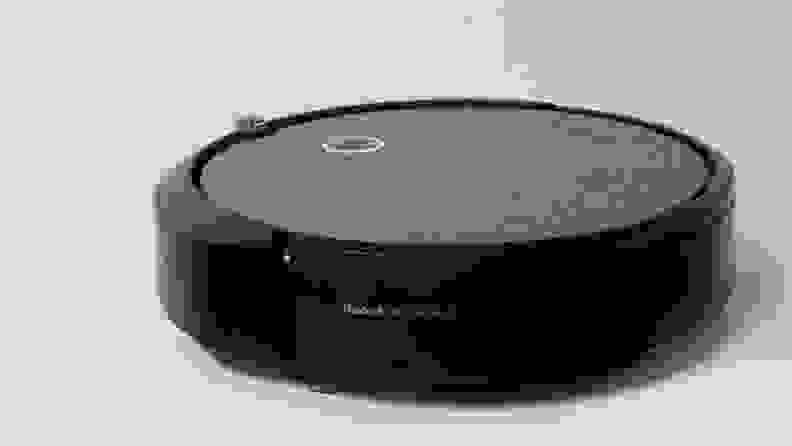 The iRobot Roomba i3+ sitting in front of a gray background.