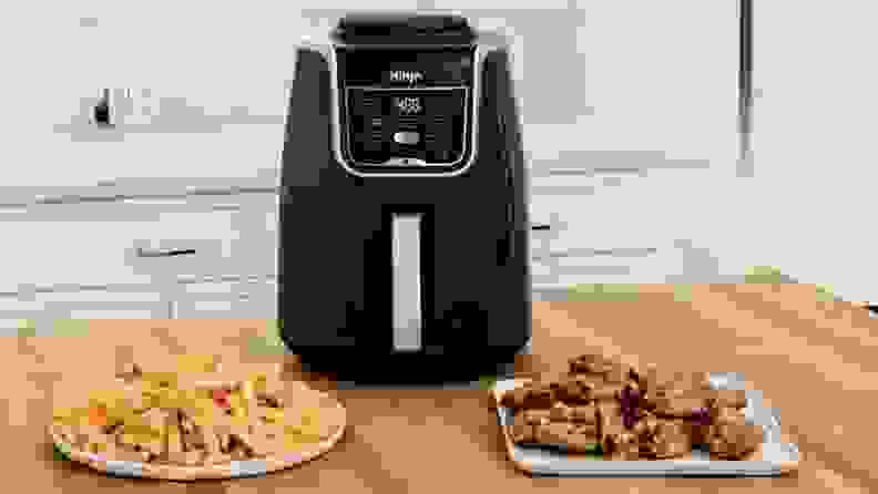 The Ninja Air Fryer XL with chicken wings and fries ready and served in separate plates.