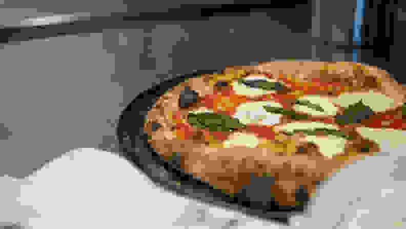 A freshly baked pizza is seen taking out of the oven.