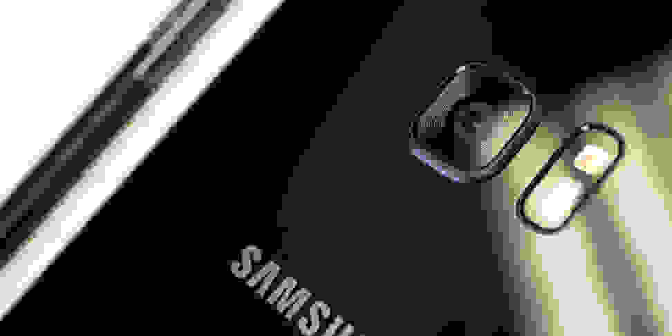Close-up of a black Samsung smartphone with a built-in camera lens and flash bulb.
