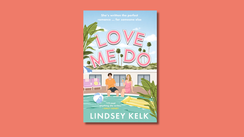 An image of the cover of the book 'Love Me Do' by Lindsey Kelk, featuring two people seated at the edge of a pool at a pastel-colored apartment complex.