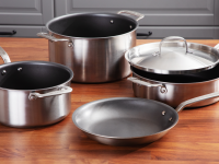 Four pieces of nonstick cookware on a wooden surface