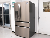 A silver French-door refrigerator stands in a lab setting against a white wall