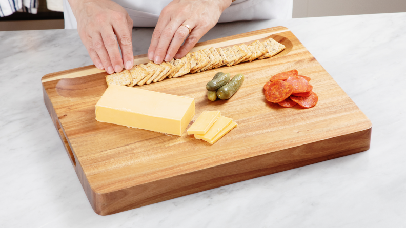 Hand arranging crackers in wooden cutting board well