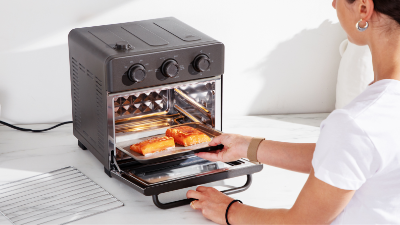 Person placing small cooking tray with two marinated salmon fillets inside the Wonder Oven.