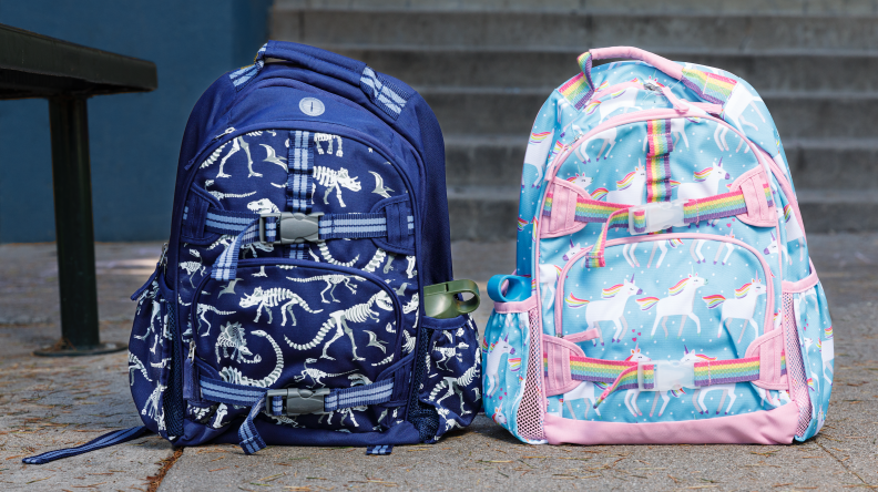 Two backpacks. One in blue with dinosaurs and one with pastel unicorns.