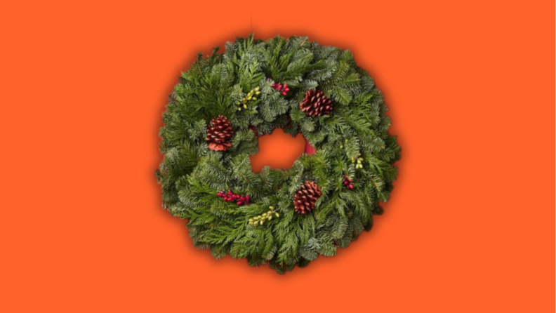 A wreath with pinecones and berries against a red background.